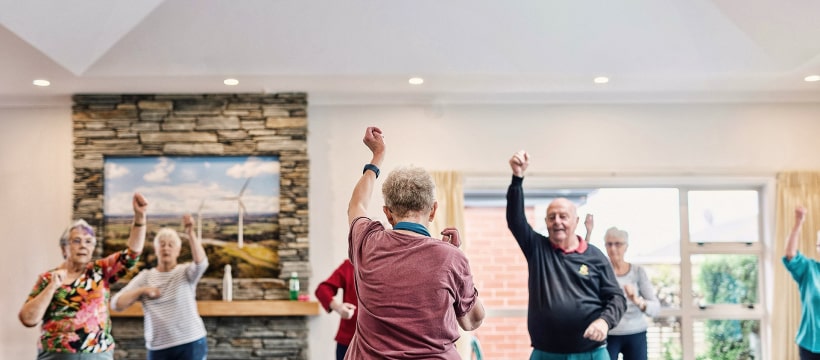 Seniors engaging in guided exercise class, promoting physical activity and social interaction in a supportive environment at Vintage Gardens memory care community.